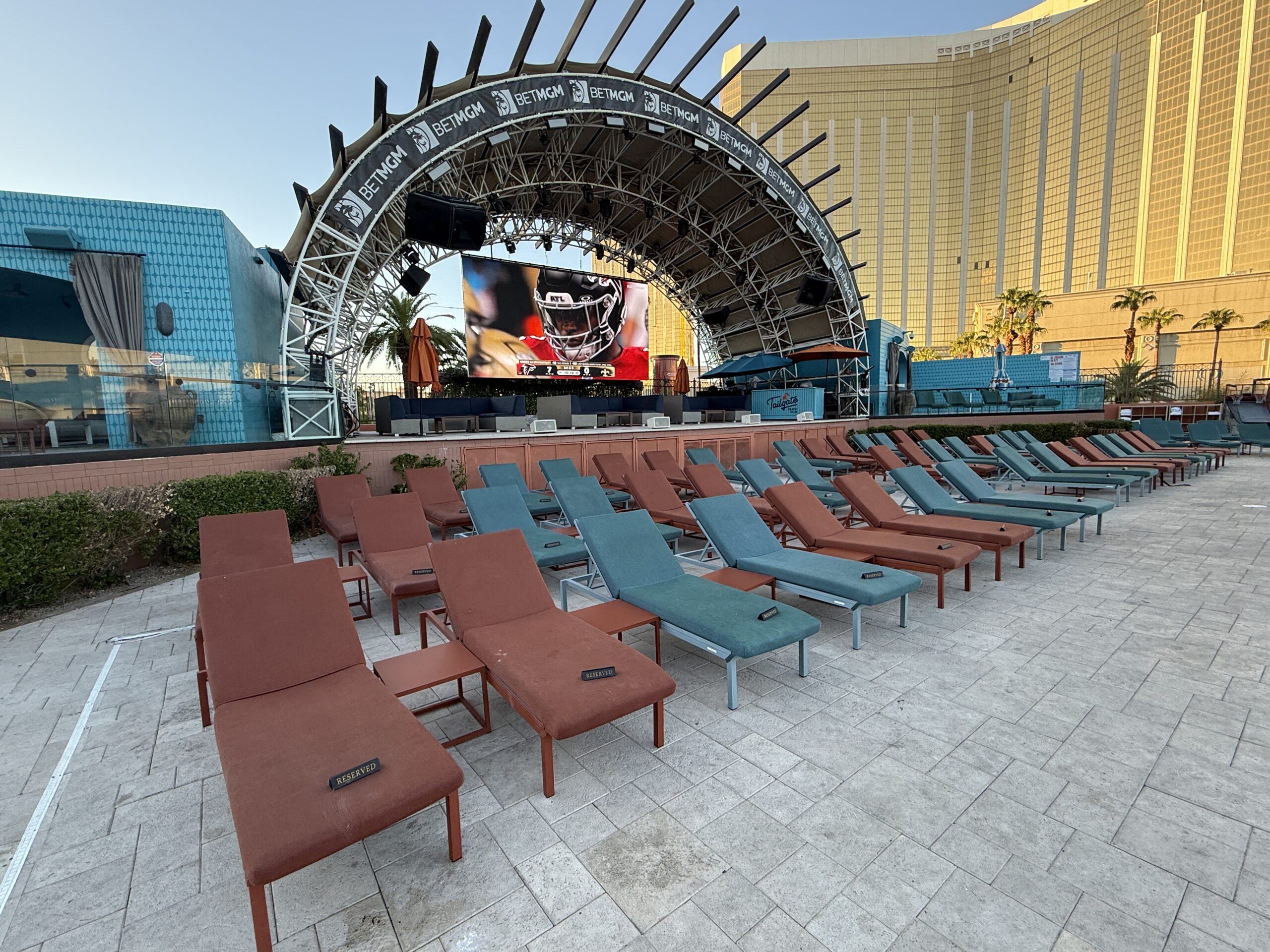 A screen showing a football game with Mandalay Bay's hotel tower behind it.