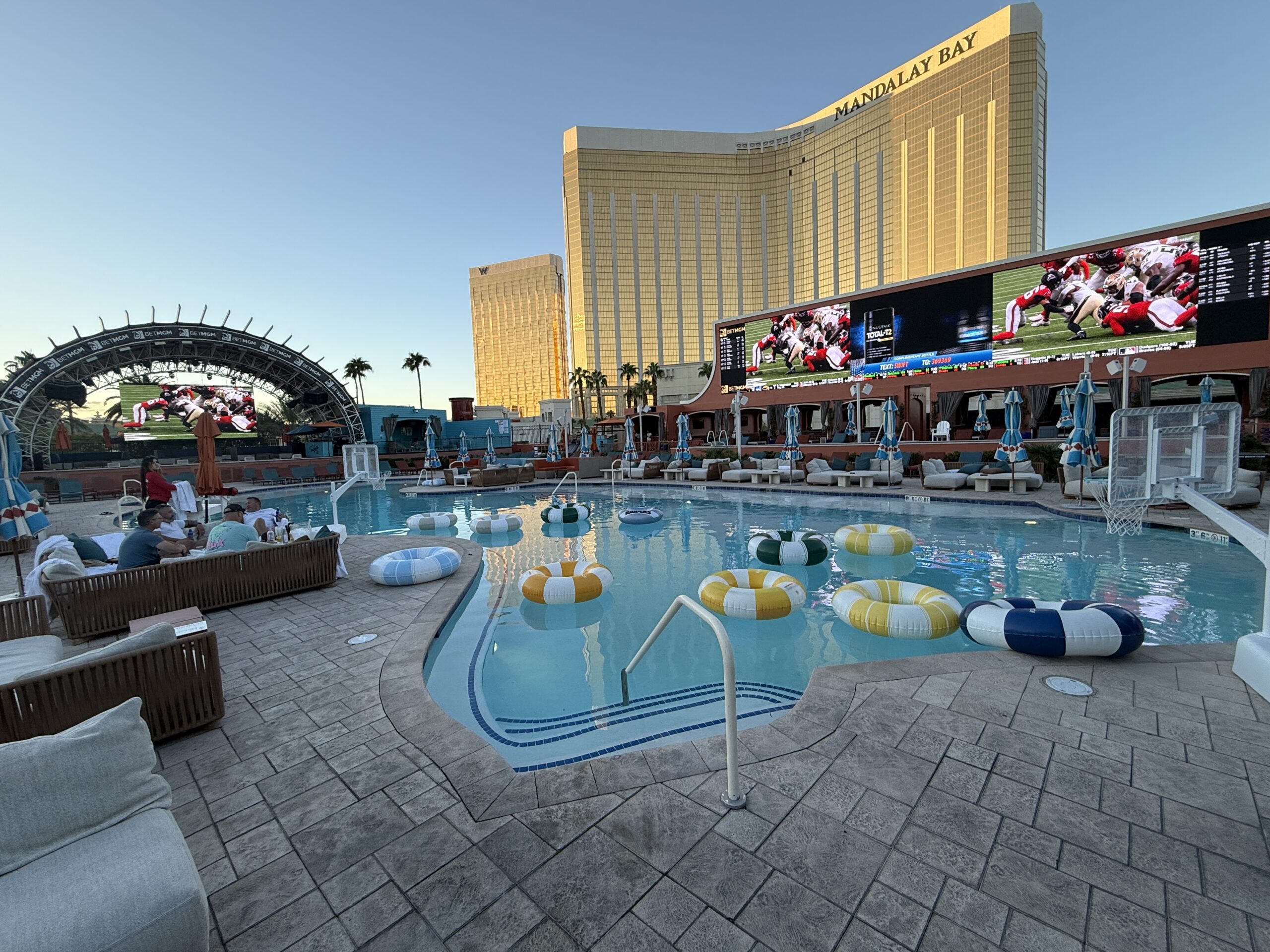A wide angle shot of Tailgate Beach Club's pool and screens, with Mandalay Bay in the background.